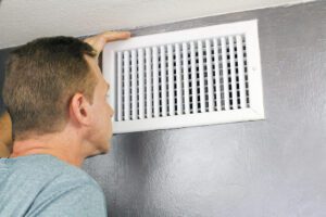 man inspecting air vent leaking water